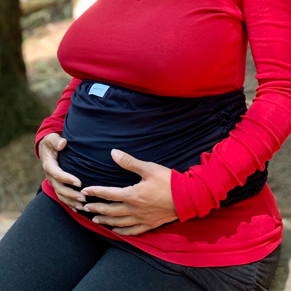 Pregnant woman wearing EMF protective baby bump band, protecting the growing baby against harmful radiation